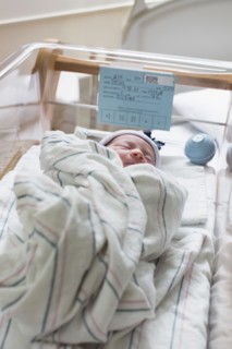 Mixed race wrapped in blanket in hospital crib