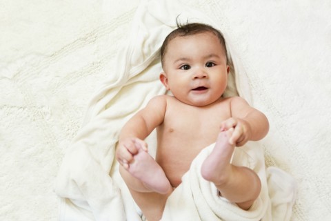 Mixed race baby playing with feet