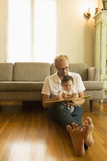 Father reading to son on living room floor