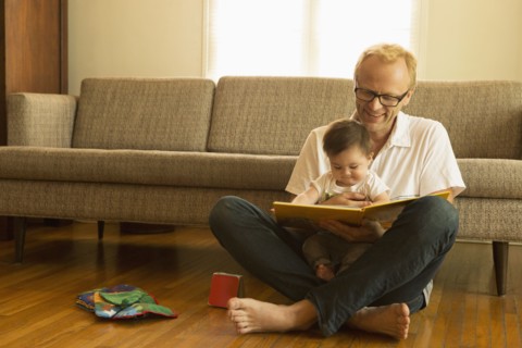 Father reading to son on living room floor