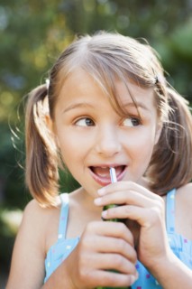 Smiling girl eating candy cigarette in backyard
