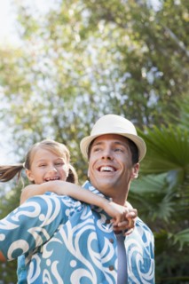 Low angle view of man carrying daughter outdoors
