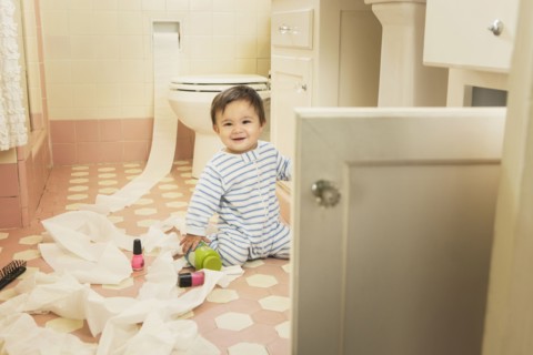 Baby boy playing in messy bathroom