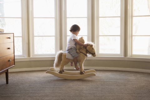 Mixed Race boy sitting on rocking horse near window