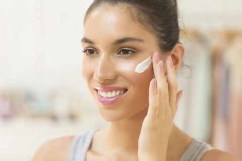 Caucasian woman applying moisturizer to face
