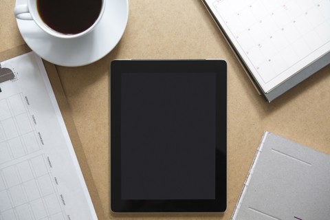 Tablet computer on table with clipboard and coffee