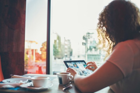 Woman using tablet computer in cafe