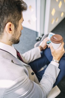Caucasian businessman drinking coffee and using cell phone