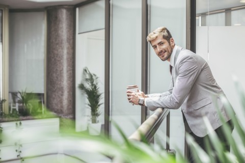Caucasian businessman drinking coffee on office balcony