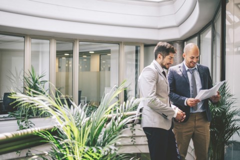 Caucasian businessmen reading paperwork on office balcony