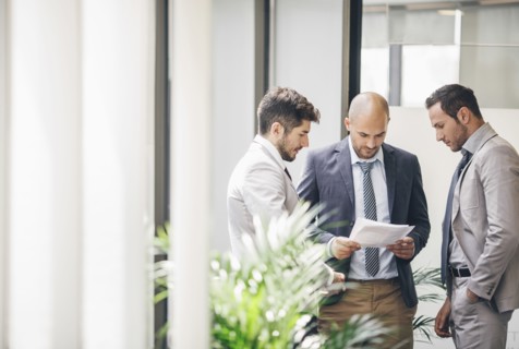 Caucasian businessmen reading paperwork in office corridor