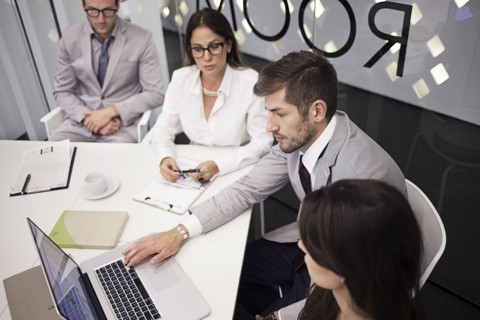 Caucasian business people using laptop in office meeting