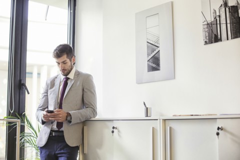 Caucasian businessman using cell phone in office