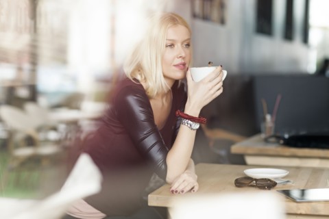 Woman drinking cup of coffee in cafe