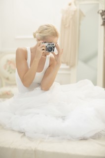 Bride photographing with vintage camera on bed
