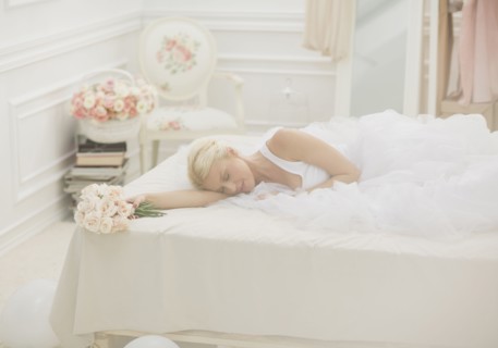Bride sleeping on bed with bouquet of flowers
