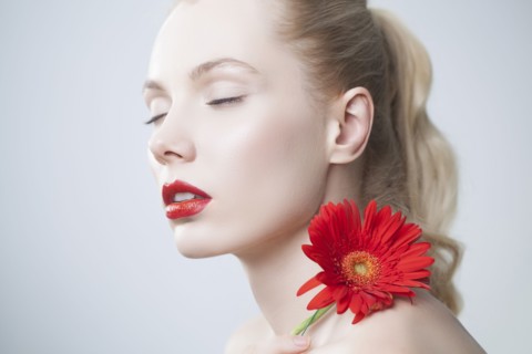 Caucasian woman with red lipstick holding matching flower