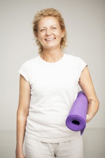 Smiling woman holding exercise mat