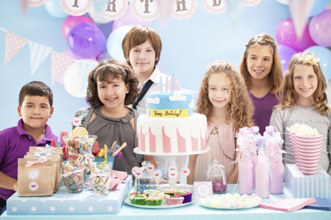 Children smiling near cake and gifts at birthday party