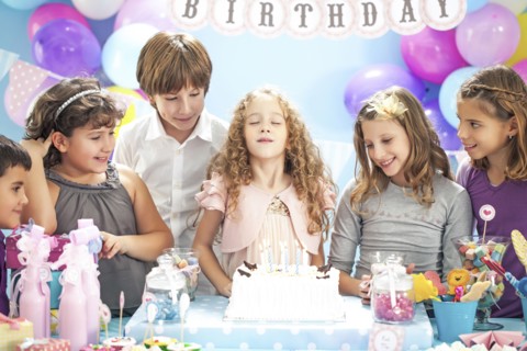 Girl wishing over birthday cake at party