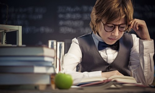 Student reading book at desk in classroom