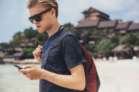 Caucasian man using cell phone on beach