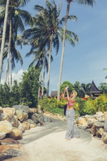 Caucasian woman photographing palm trees on beach