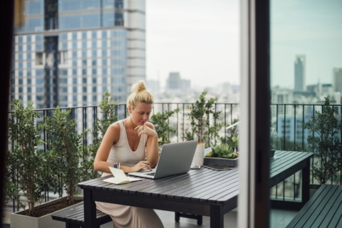 Caucasian woman using laptop on balcony