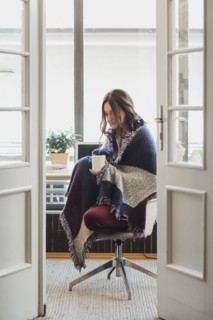 Caucasian woman in blanket drinking cup of coffee