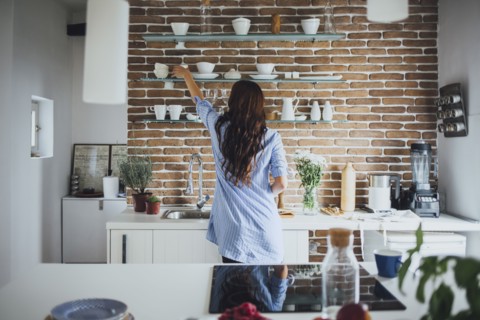 Caucasian woman reaching for dishes in kitchen
