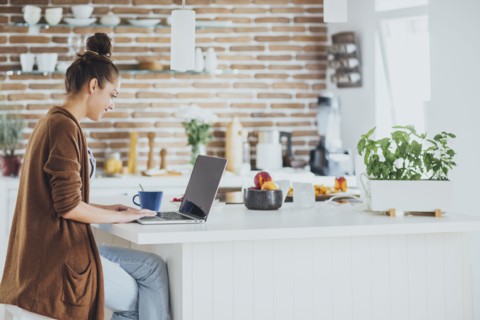 Caucasian woman using laptop in kitchen