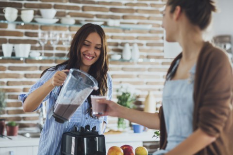 Caucasian women pouring smoothie in kitchen