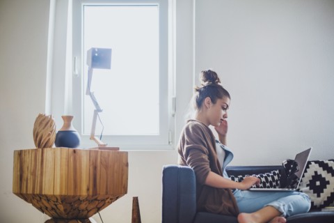 Caucasian woman using laptop on sofa