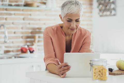 Older Caucasian woman using digital tablet in kitchen
