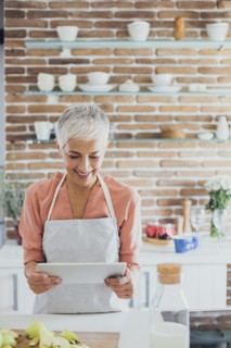 Older Caucasian woman using digital tablet in kitchen
