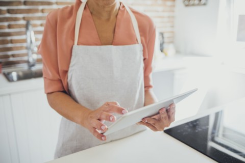 Older Caucasian woman using digital tablet in kitchen