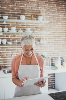 Older Caucasian woman using digital tablet in kitchen