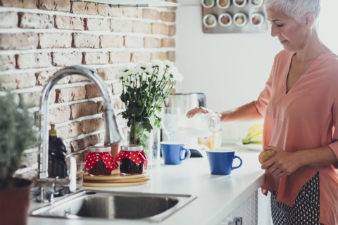 Older Caucasian woman making coffee in kitchen