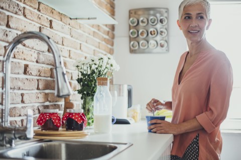 Older Caucasian woman stirring coffee in kitchen