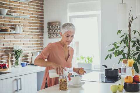 Older Caucasian woman pouring milk in kitchen