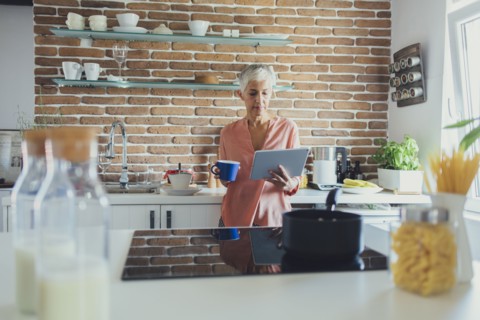 Older Caucasian woman using digital tablet in kitchen