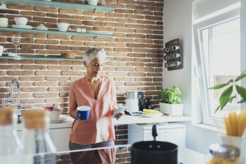 Older Caucasian woman using cell phone in kitchen