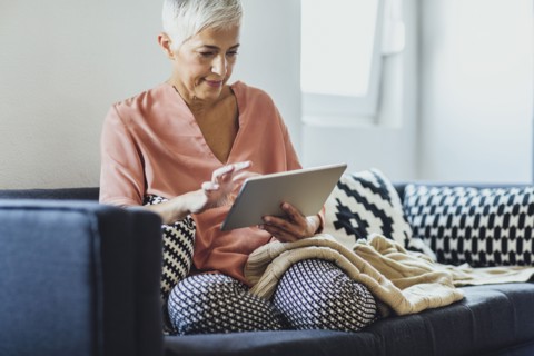 Older Caucasian woman using digital tablet on sofa