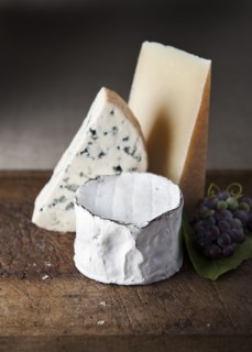 Artisanal cheese and grapes on wooden table