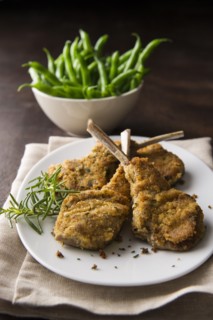 Breaded lamb chops on plate with bowl of green beans