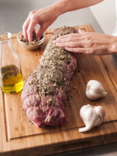 Hands rubbing garlic and pepper onto tenderloin