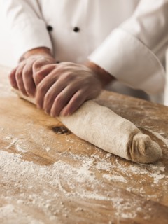 Hands of baker rolling dough