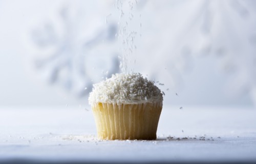 White sprinkles falling on vanilla cupcake
