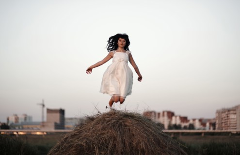 Caucasian woman jumping on haystack