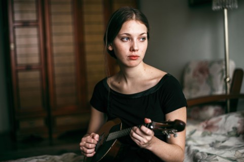 Caucasian woman playing ukulele in bedroom